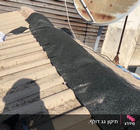 תיקון גג עם יריעות ביטומניות וצל של אדם